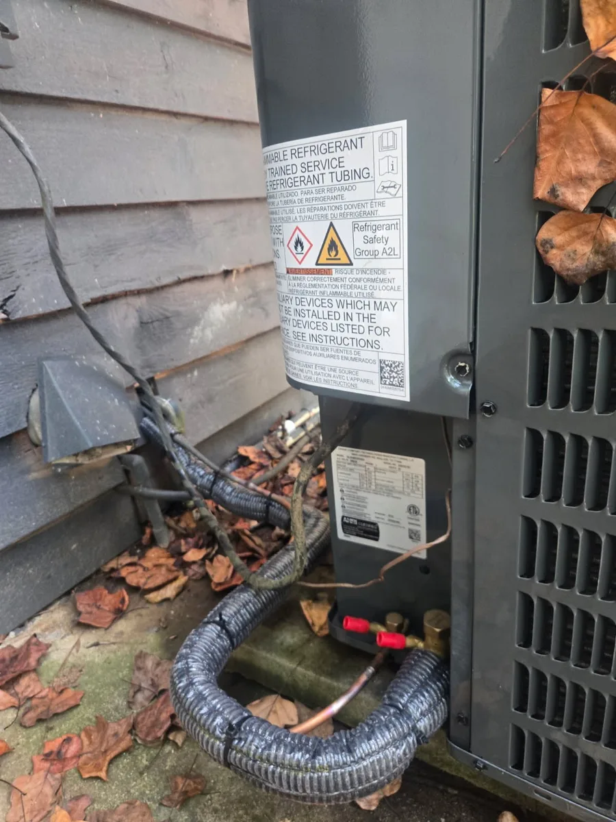 Outdoor unit carrying an A2L refrigerant safety label, with an insulated line set and service valves connected